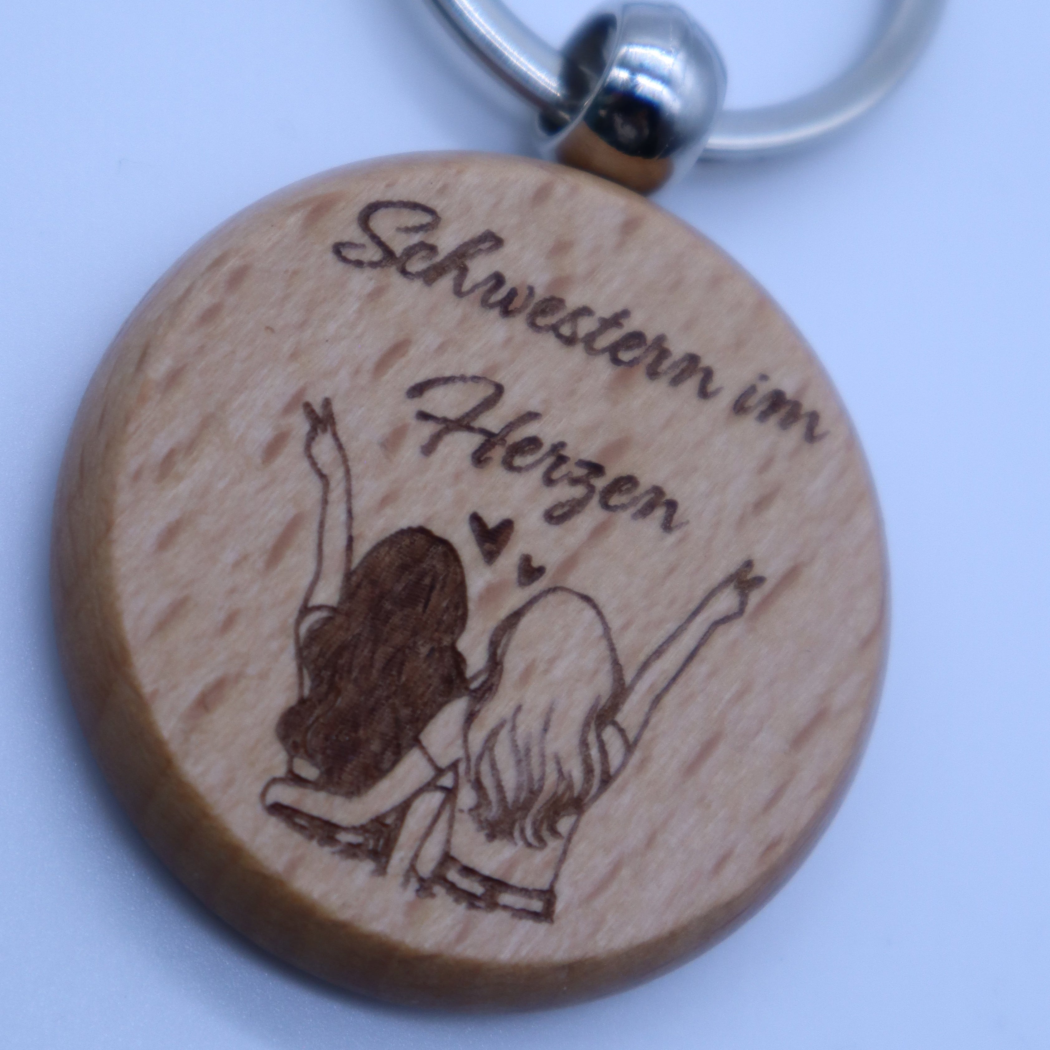 Detailaufnahme Gravur Schwestern im Herzen auf Holz Schlüsselanhänger personalisiertes Geschenk